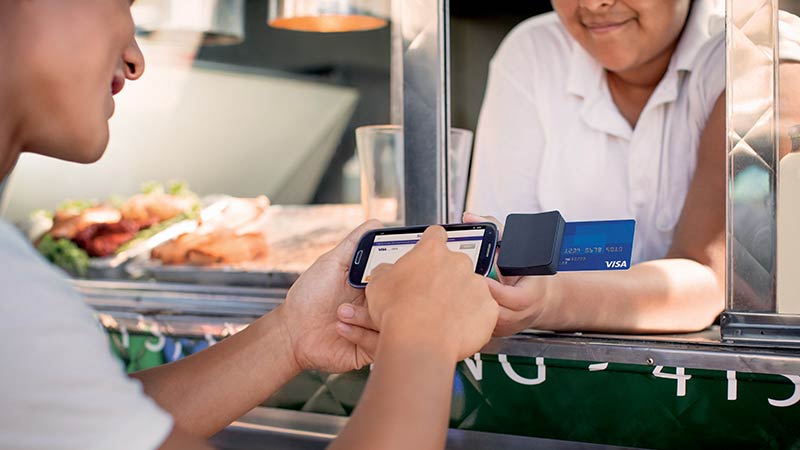Visa コンシューマー トランザクション コントロール Customer completing a transaction using a mobile credit card reader at a food truck.